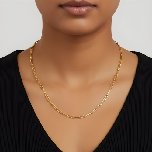 Gold chain necklace worn by a person against a neutral background