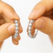Celeste diamond hoops in hands showcasing their sparkling cubic zircons and sleek design.