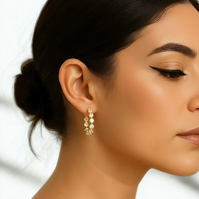 Celeste diamond hoops in gold vermeil worn by a woman, showcasing round-cut cubic zircons that reflect light.