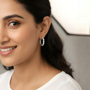 Woman wearing Celeste diamond hoops, showcasing their sparkling cubic zircon gems and sleek design.