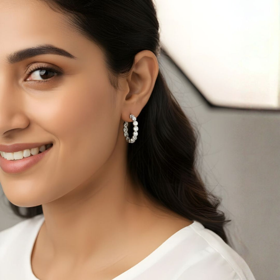 Woman wearing Celeste diamond hoops, showcasing their sparkling cubic zircon gems and sleek design.