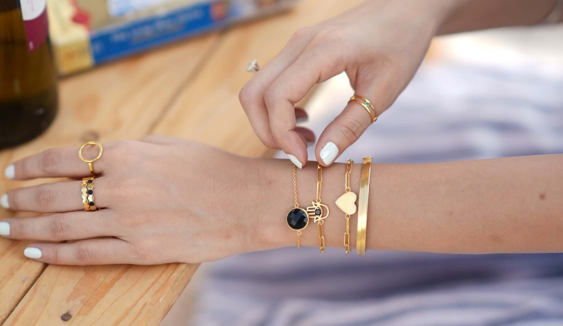 Close-up of a hand with multiple gold bracelets, illustrating the concept of gold plating definition.