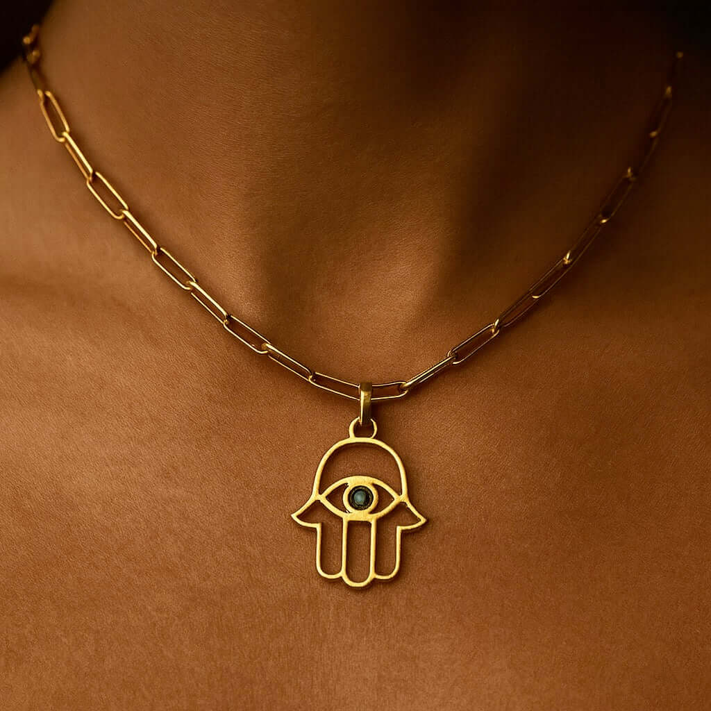 Hamsa Pendant in gold, featuring an eye design, worn on a delicate chain, symbolizing protection and good luck.