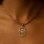 Hamsa Pendant in gold, featuring an eye design, worn on a delicate chain, symbolizing protection and good luck.