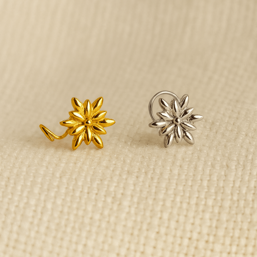 Gold and silver flower-shaped nose pins on a beige fabric background