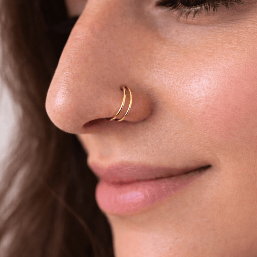 The Reya Double Band Nose Ring worn by a woman, featuring two fine parallel bands in a close-up shot.