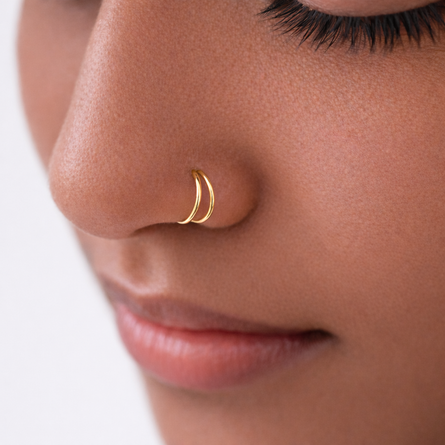 The Reya Double Band Nose Ring worn on a model's nose, showcasing a minimal gold design.