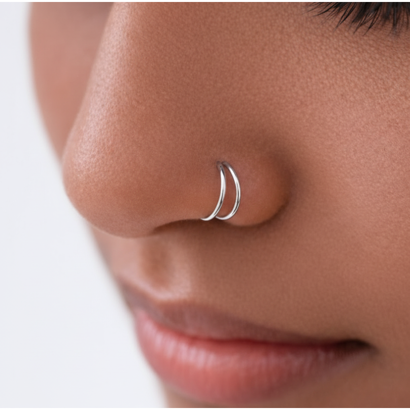 The Reya Double Band Nose Ring worn close to the nose, showcasing two fine parallel bands in 92.5 sterling silver.