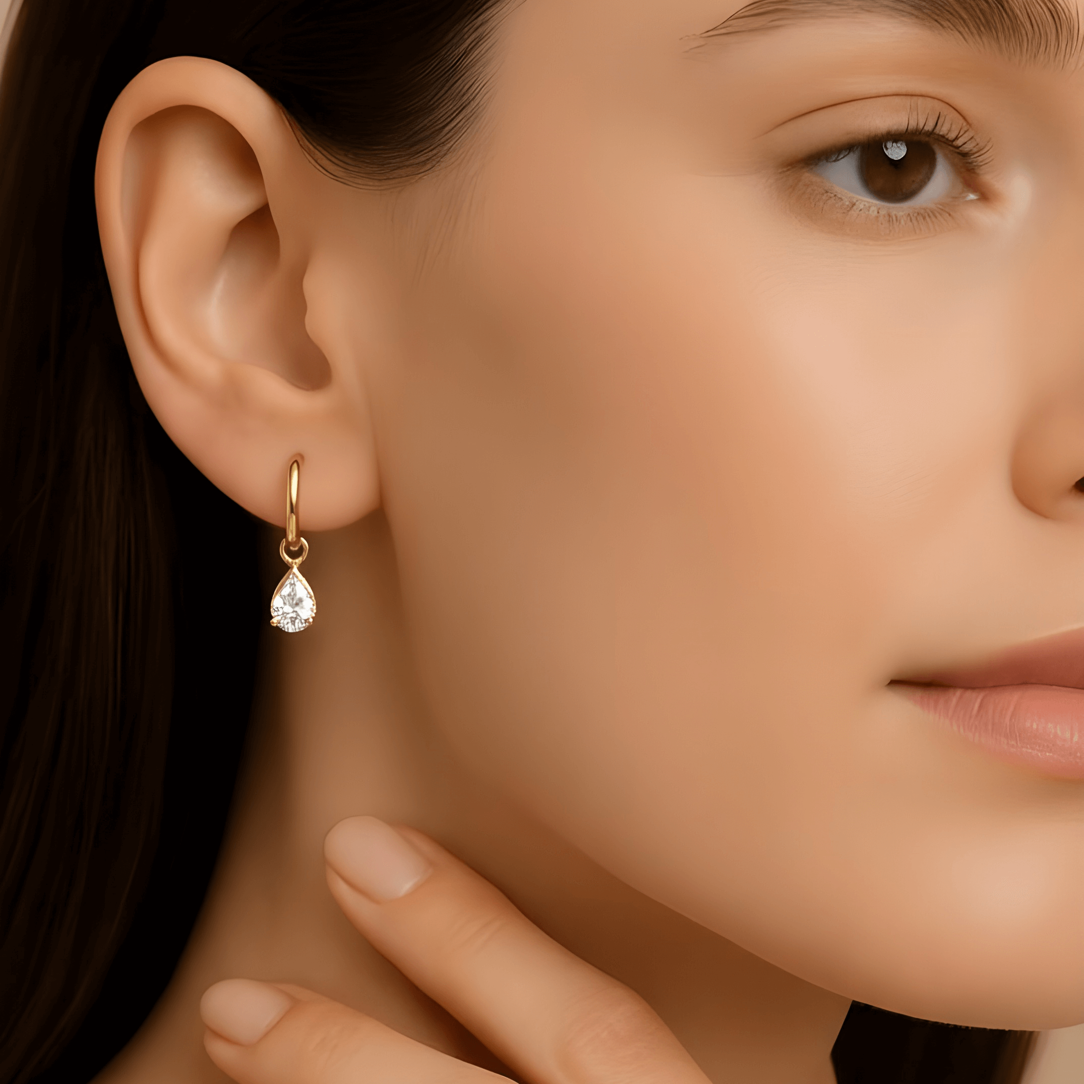 Close-up of a woman wearing a gold earring with a clear gemstone.