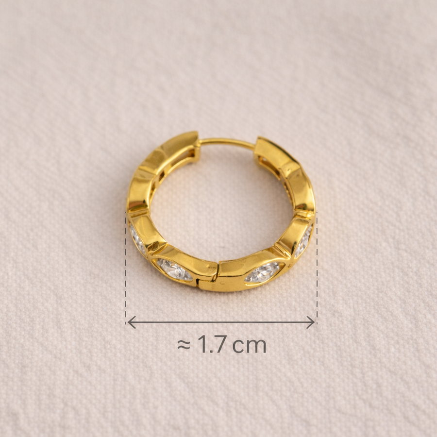 Gold hoop earring on a textured beige background with measurement label