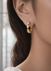 Close-up of a person wearing gold hoop earrings with a blurred background