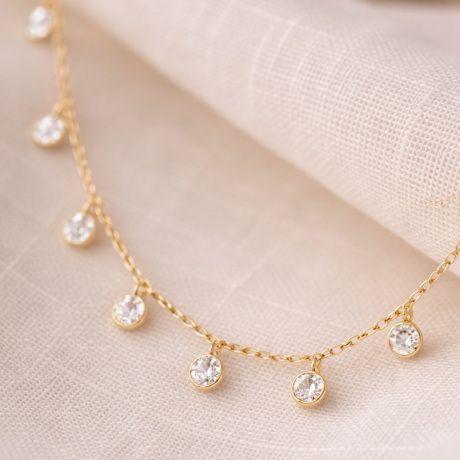Gold necklace with small diamonds on a beige fabric background