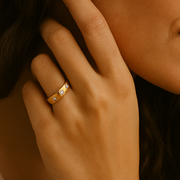 Close-up of a hand wearing a gold ring with a blurred background