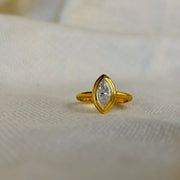 Gold ring with a diamond on a beige fabric background