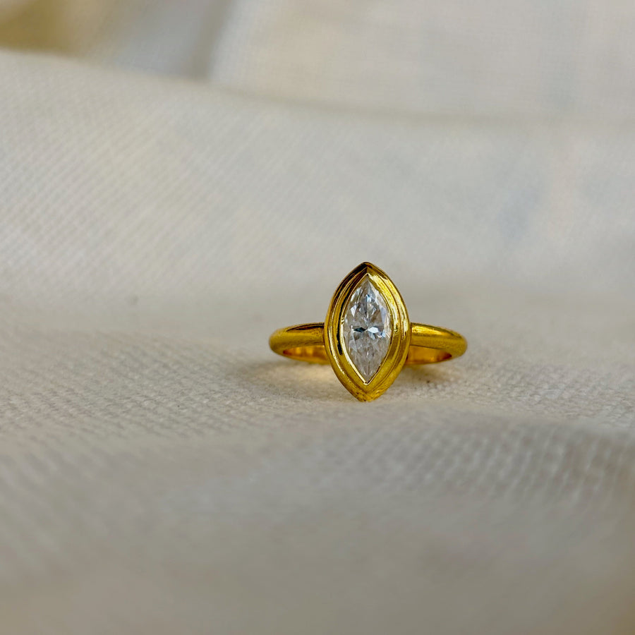Gold ring with a diamond on a beige fabric background