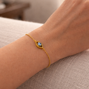Netra - The contemporary evil eye bracelet worn on a wrist, showcasing its 18k gold vermeil and blue gemstone.